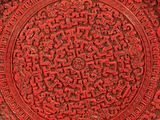 a close up of a red plate with intricate designs on it