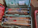 une mallette verte posée par terre, contenant des outils