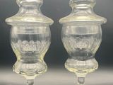 pair of clear glass candy jars on pedestals with lids