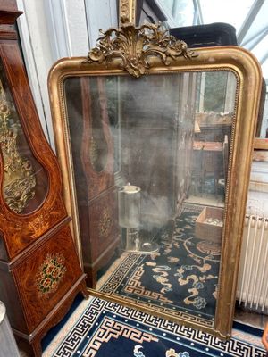 a large mirror sitting on the floor next to a grandfather clock