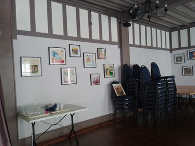 des tables et des chaises dans une pièce où sont accrochés des tableaux au mur