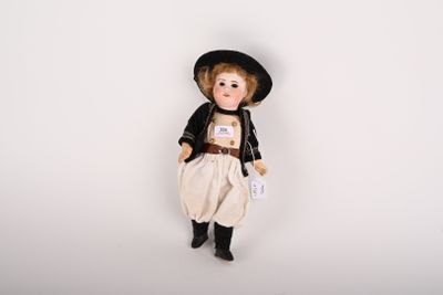 une petite poupée qui porte un chapeau et une salopette