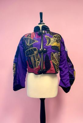 purple and black jacket on a mannequin stand against a pink wall