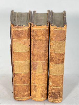 trois vieux livres posés l'un sur l'autre sur une surface blanche
