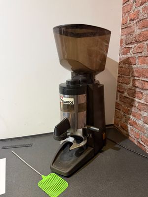 a coffee grinder sitting on the floor next to a brick wall