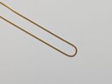 un gros plan d'un collier avec une chaîne en or sur une surface blanche