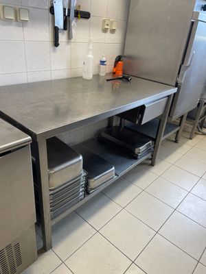 un plan de travail en acier inoxydable dans une cuisine équipée d'un réfrigérateur et d'un lave-vaisselle
