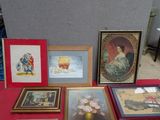 many framed pictures on a red table with a red table cloth