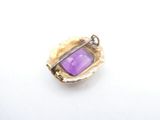 a close up of a purple glass pendant on a white surface