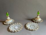 three white and gold candlesticks with green tops
