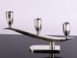 a silver candle holder with three silver cups on it