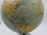 un petit globe posé sur un socle, sur une surface blanche