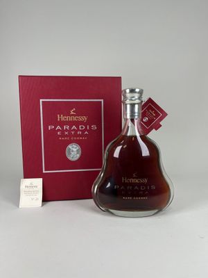 une bouteille de cognac Hennessy devant une boîte rouge