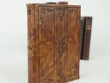 an old book with a leather cover sitting on top of a white surface