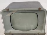 an old television sitting on a table with a white wall behind it