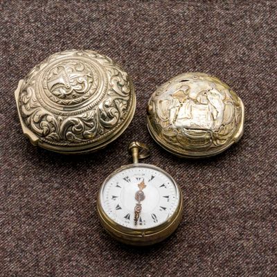 deux montres de poche en or et une montre de poche en or posée sur une surface marron