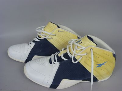 pair of yellow and blue sneakers with white laces on a gray surface