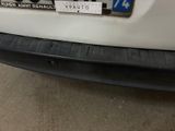 the rear bumper of a white car with a sticker on it ' s bumper
