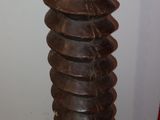 a tall wooden sculpture with a red vase on top of it