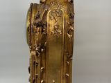 a gold clock with a bird on top of it