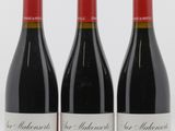 trois bouteilles de vin rouge sont posées côte à côte sur une surface blanche