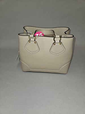 a white purse with a pink handle on a table