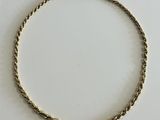 a close up of a gold bracelet on a white surface