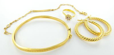 un gros plan d'un bracelet et d'une bague en or posés sur une surface blanche