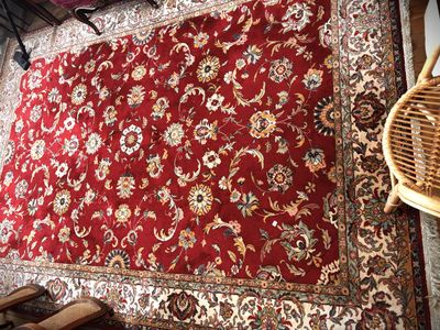 a red rug on the floor next to a wicker chair