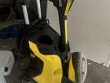 un nettoyeur haute pression jaune et noir posé à côté d'une poubelle