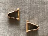 une paire de boucles d'oreilles en or posées sur une surface grise