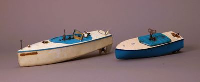 two toy boats sitting next to each other on a gray surface