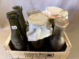 une caisse en bois remplie de bouteilles et de bocaux posée sur une table