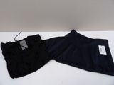 two pairs of black pants sitting on top of a white table