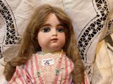 a doll that is sitting on a table with a lace tablecloth