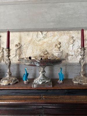 three silver candles sitting on a table in front of a wall