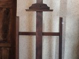 a wooden easel with a cross on it in front of a white wall