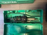 a green box with a drill in it on the floor