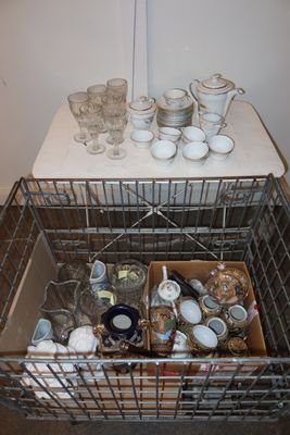 a metal basket filled with dishes and cups on a table