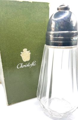 un salière et une poivrière en verre posées devant une boîte verte