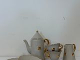 a white table with a tea pot and a plate on it