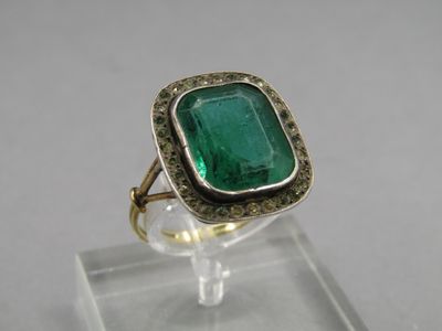 a close up of a ring with a green stone in it