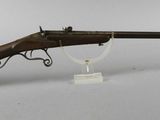 a rifle with a wooden barrel on a stand on a white surface