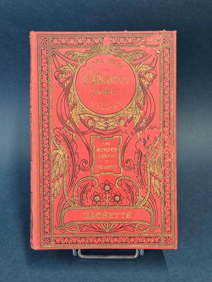 un livre rouge orné d'inscriptions dorées, posé sur une surface bleue