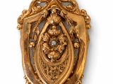 an image of a gold broochle with a bird and flowers on it