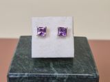 une paire de boucles d'oreilles en pierre violette posées sur un bloc de marbre