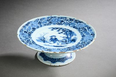 une assiette bleue et blanche posée sur un socle, sur une table