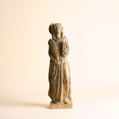 une petite statue représentant une femme debout sur une surface blanche