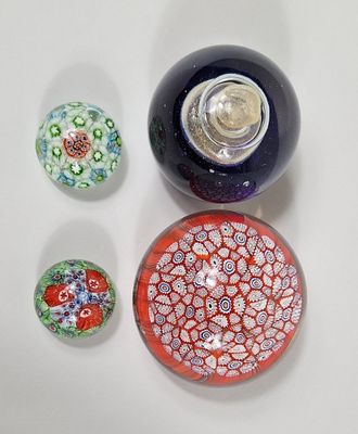 trois boules de verre de couleurs différentes posées sur une surface blanche