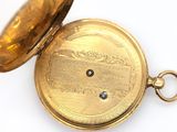 a gold pocket watch that is open on a white surface